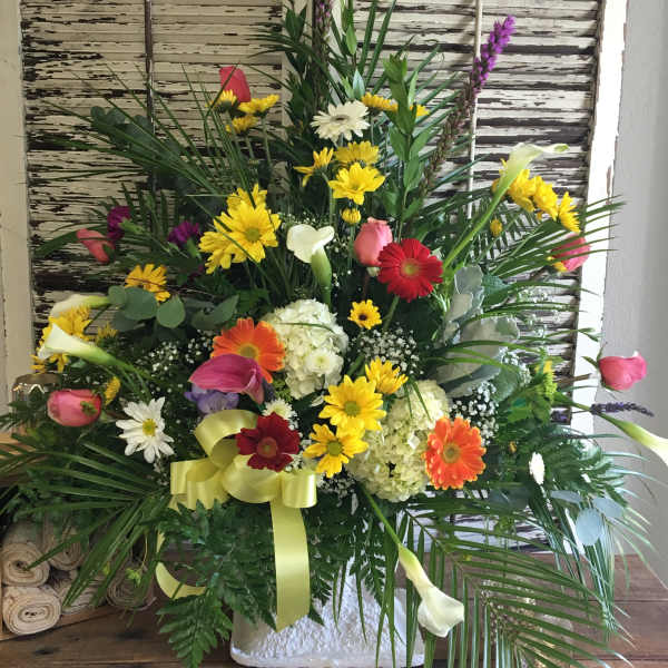 Large mixed flower arrangement with bright gerberas, calla lilies, and roses