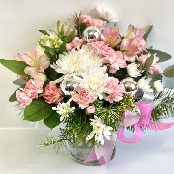 Pink and white bouquet in a glass vase with silver ornaments and ribbon