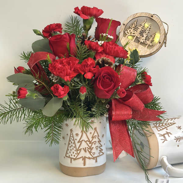 Red roses and carnations in a holiday mug with a red ribbon