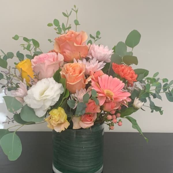 Mixed bouquet of pastel flowers in a green glass vase