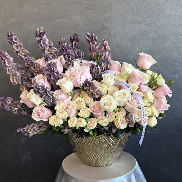 Pink and white roses in a gold textured vase with tall purple blooms