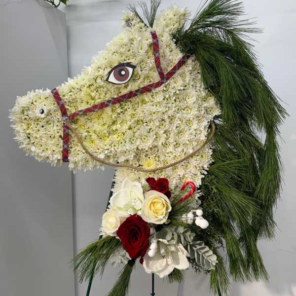 Horse-shaped floral standing spray with white blooms, red roses, and pine accents