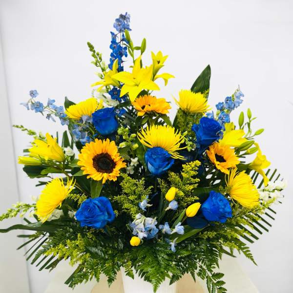 Blue and yellow mixed bouquet in a white container