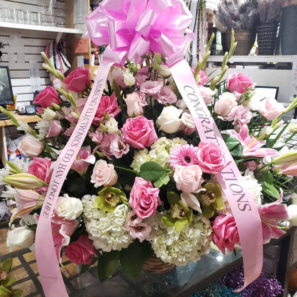 Large pink and white floral arrangement with a pink bow and ribbons
