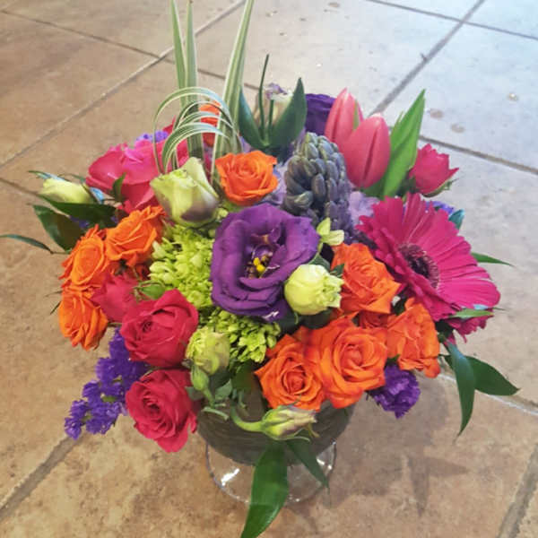 Colorful mixed bouquet in a clear glass vase with roses and gerbera daisies