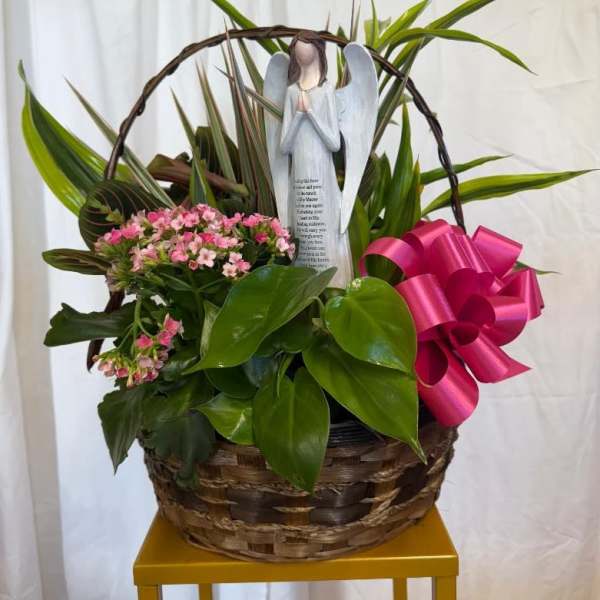 Basket of pink flowers with an angel figurine and bright ribbon