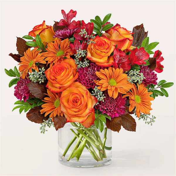 Orange roses and purple mums in a clear glass vase
