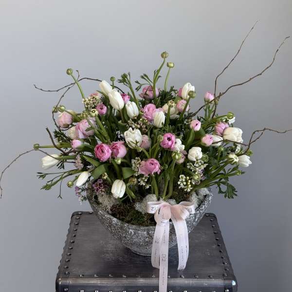Pink and white floral arrangement in a stone bowl with ribbon