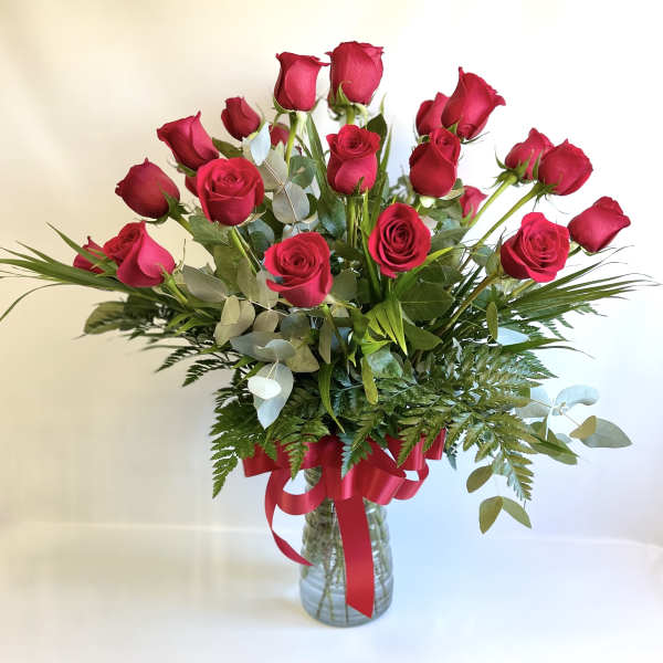 Bouquet of red roses in a glass vase with a red ribbon
