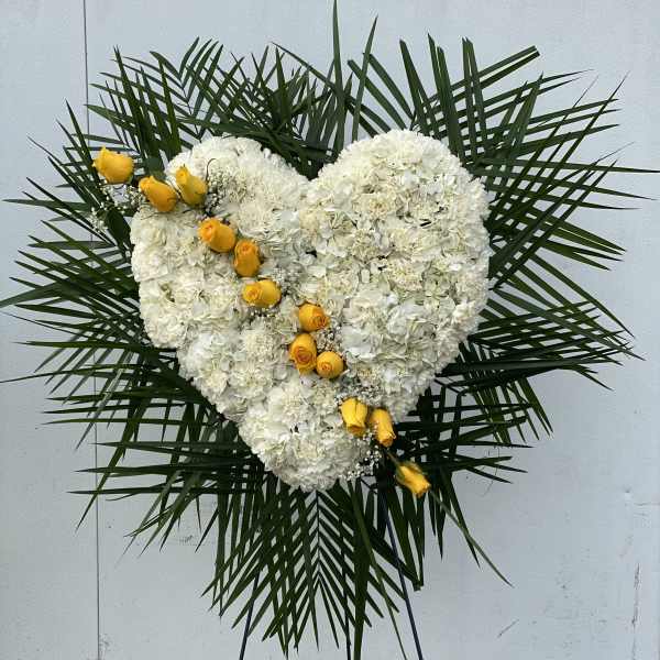 Heart-shaped white floral spray with yellow roses on a stand