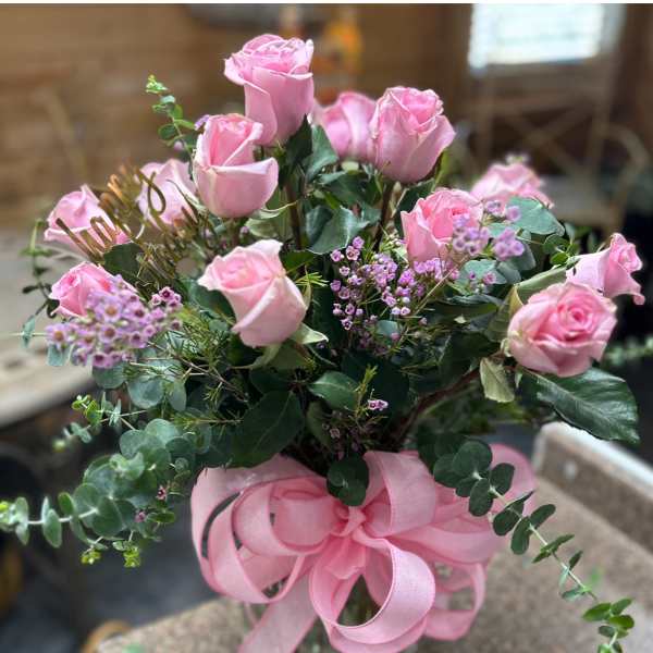 Pink roses in a glass vase with a pink ribbon bow