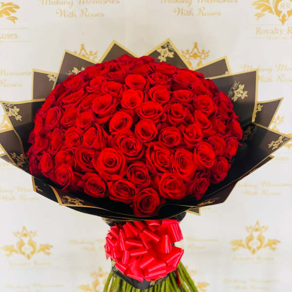 Large bouquet of red roses wrapped in black paper with a red bow