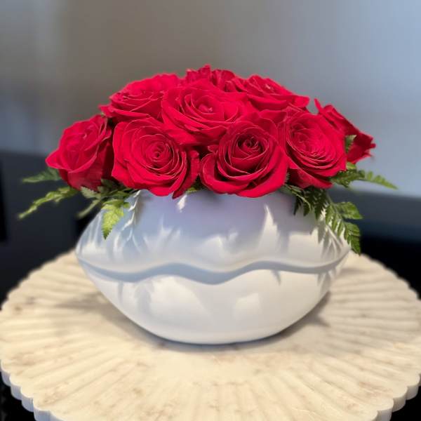 Red roses arranged in a white round vase