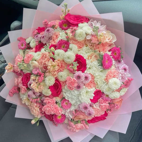 Large pink and white mixed bouquet wrapped in translucent paper