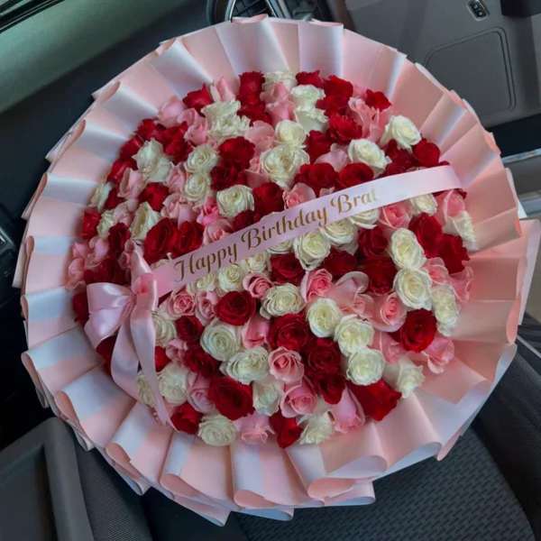 Round bouquet of red, pink, and white roses with a birthday ribbon