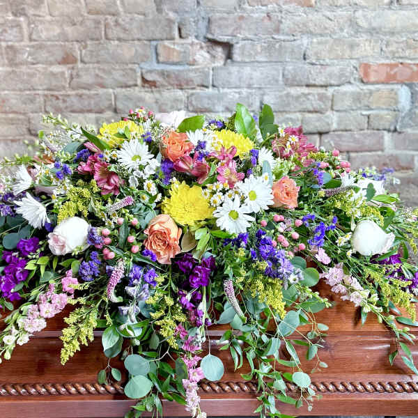 Large casket spray with mixed pink, white, yellow, and purple flowers