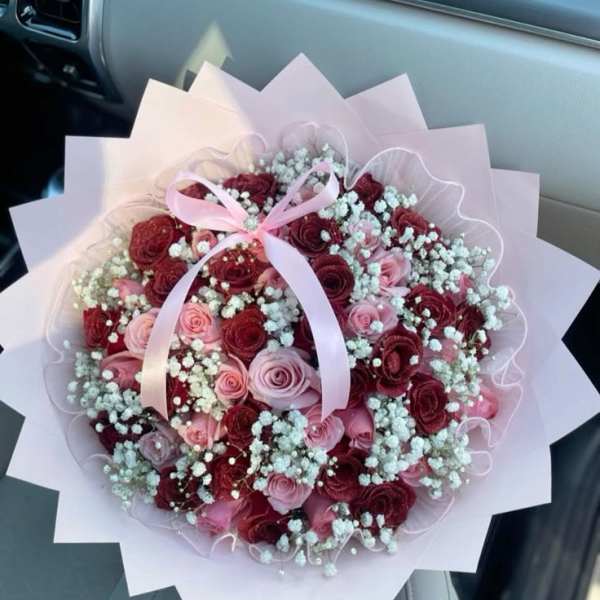 Bouquet of pink and burgundy roses with baby's breath and a pink ribbon