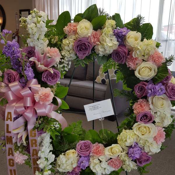 Large floral wreath with pink, purple, and white flowers on a stand