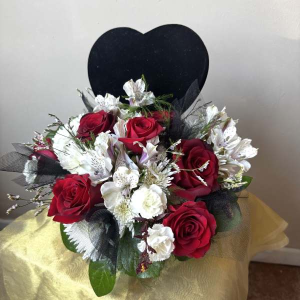 Red roses and white flowers in a bouquet with a black heart backdrop