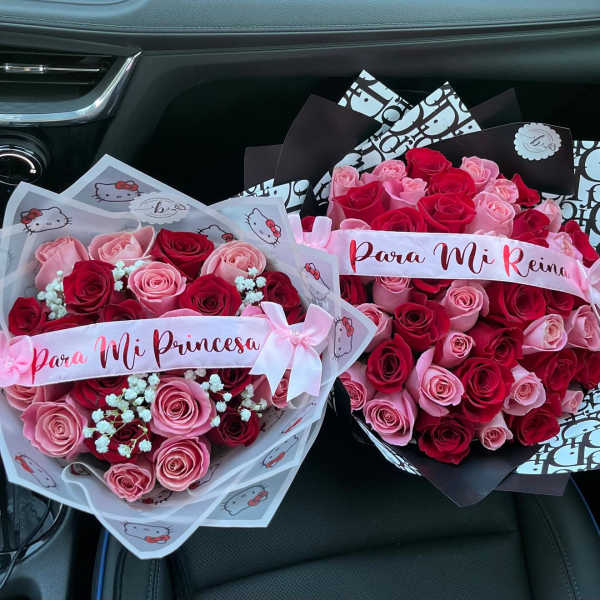 Two bouquets of pink and red roses with ribbon banners in a car seat