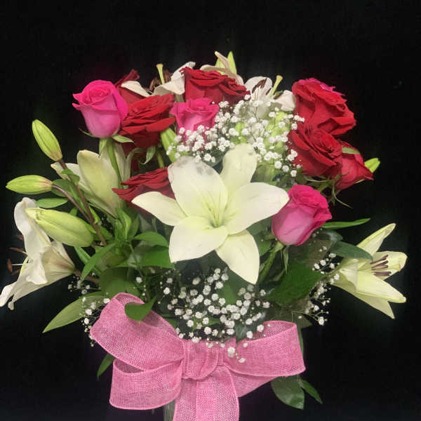 Bouquet of red and pink roses with white lilies in a glass vase