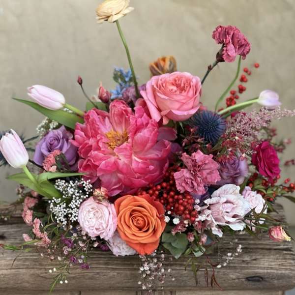 Mixed bouquet of pink, purple, and orange flowers on a wooden surface