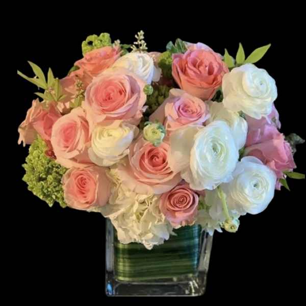 Pink and white roses arranged in a clear square vase