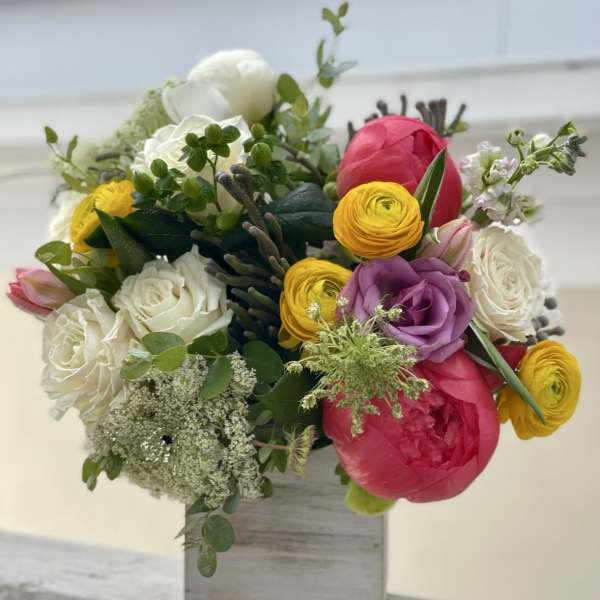 Colorful bouquet of roses and ranunculus in a wooden box