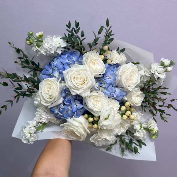Bouquet of white roses and blue hydrangeas with greenery