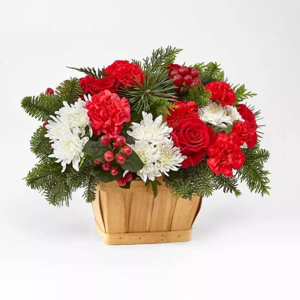 Red and white flowers arranged in a wooden basket with evergreen accents