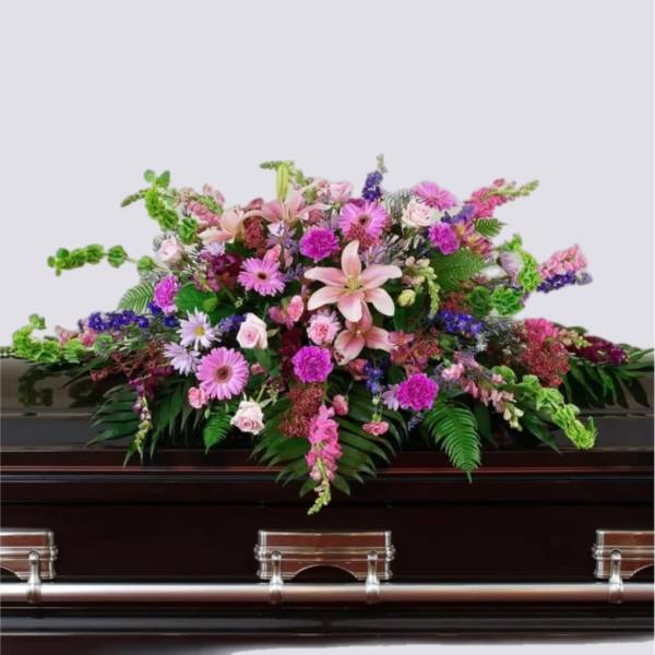Large pink and purple floral spray on a dark casket