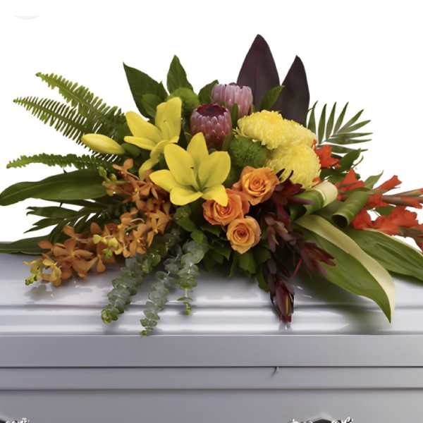 Tropical floral spray with yellow lilies and orange roses on a casket
