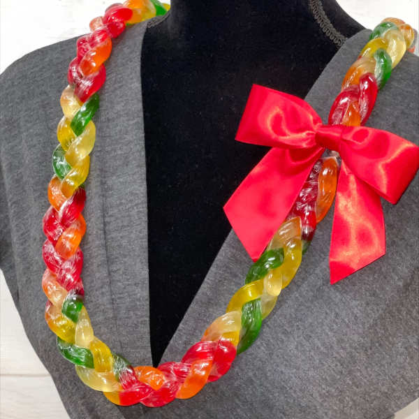 Colorful twisted candy lei necklace with red bow displayed on a gray dress form