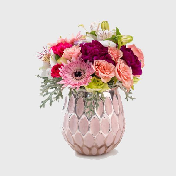 Mixed pink and peach flowers in a pink ceramic vase