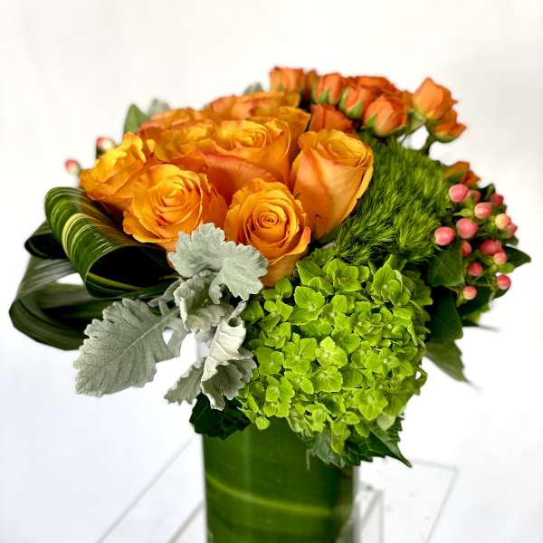 Orange roses and green hydrangea in a glass vase