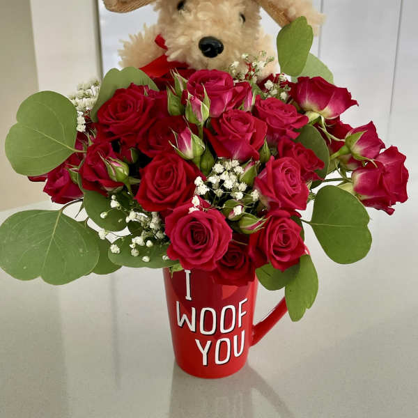 Red roses in a mug with a plush dog peeking over the top