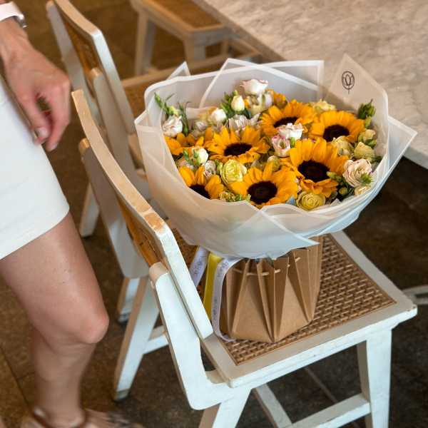 Bouquet of sunflowers and small cream roses wrapped in white paper