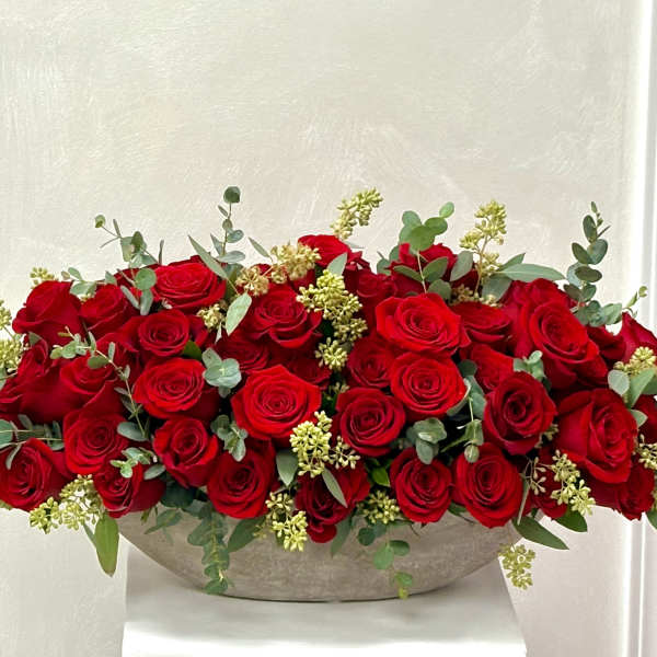 Low arrangement of red roses in a shallow bowl with eucalyptus accents