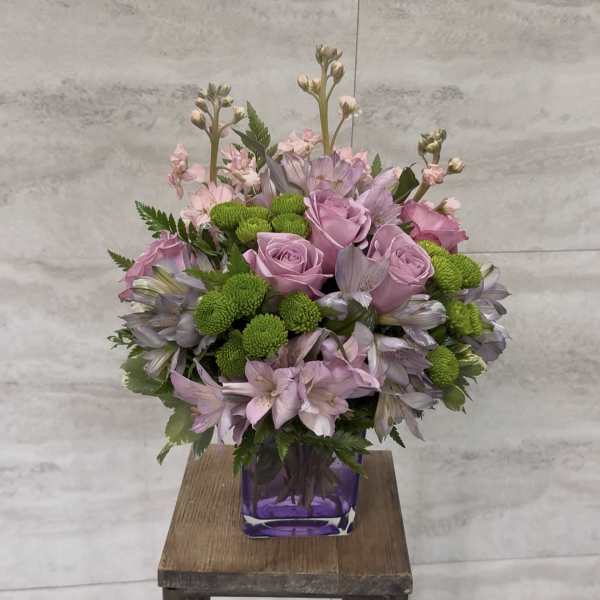 Pink roses and lavender flowers arranged in a purple vase