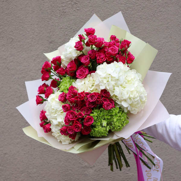 Bouquet of pink roses and white hydrangeas wrapped in pastel paper