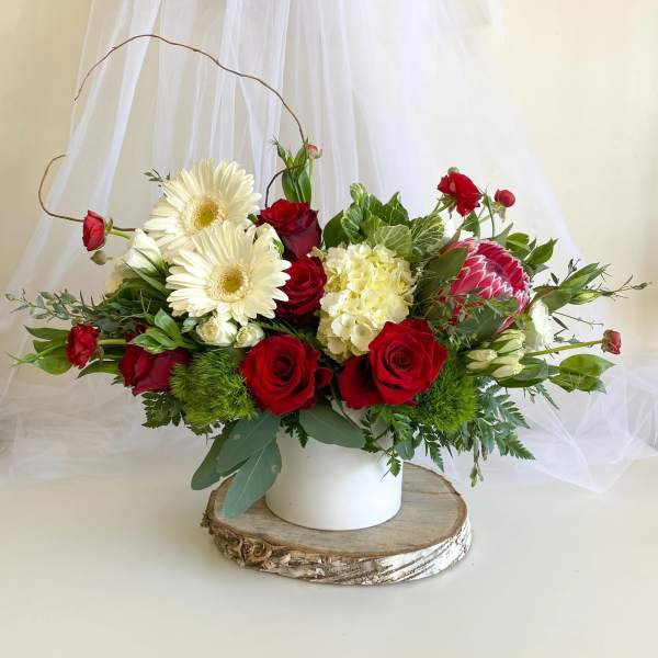 Red roses and white daisies arranged in a white vase