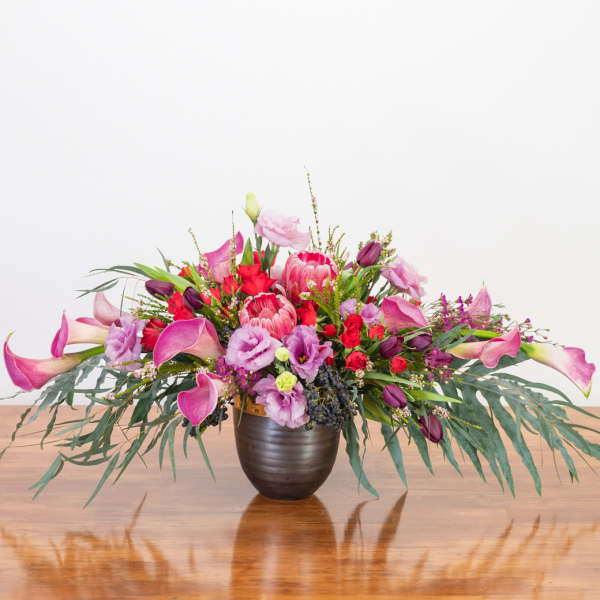 Large pink and purple floral arrangement in a dark vase