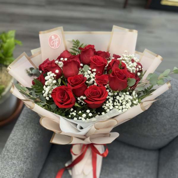 Bouquet of red roses with baby's breath in beige wrap