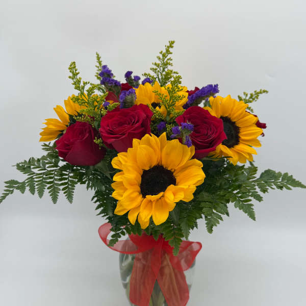 Bouquet of red roses and yellow sunflowers in a glass vase