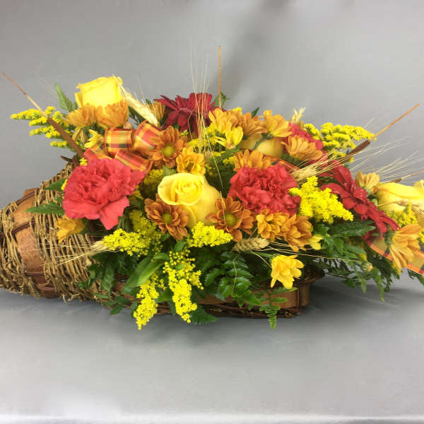 Basket arrangement with yellow roses, red carnations, and daisies