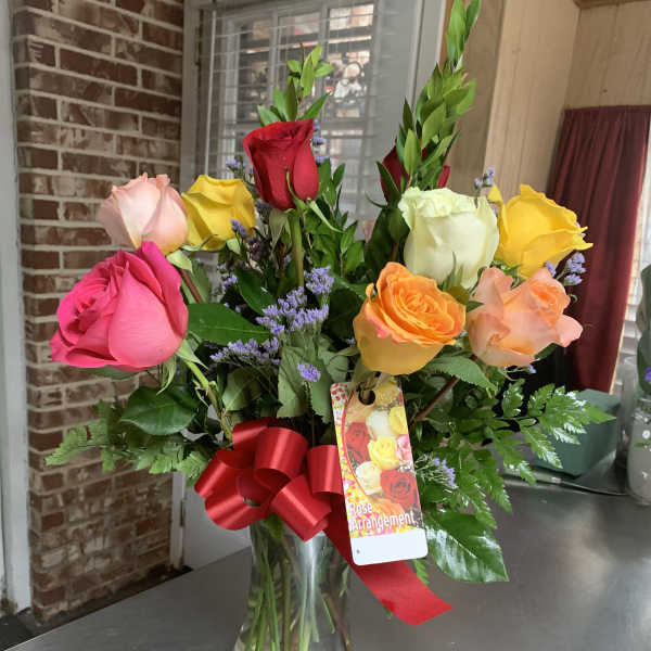 Mixed roses in a clear glass vase with a red ribbon