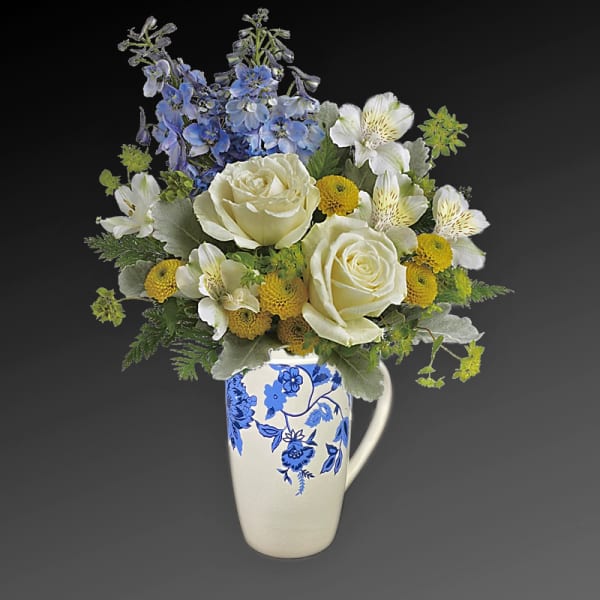 Blue and white flower arrangement in a floral ceramic pitcher