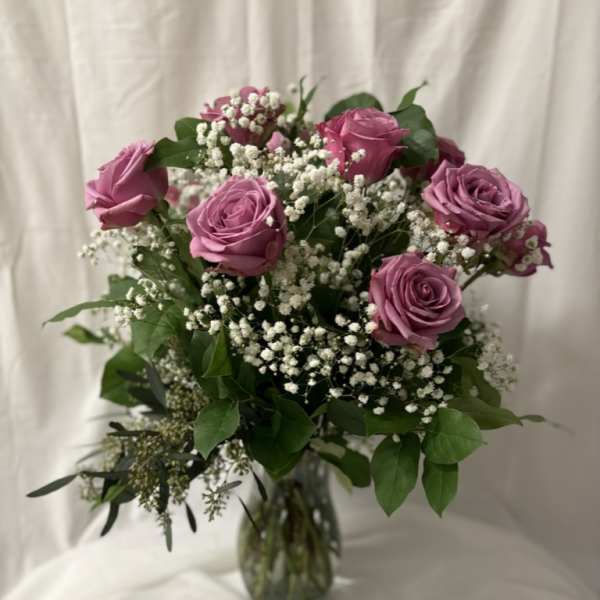 Bouquet of lavender roses and white baby's breath in a glass vase