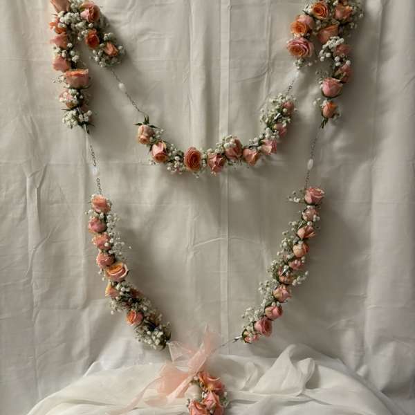 Pink rose garland arranged in a heart shape with a ribbon bow