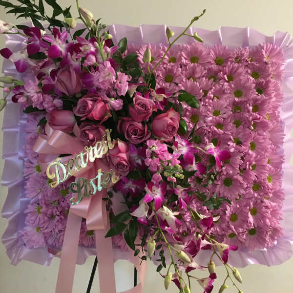 Pink floral standing spray with roses and daisies on a lavender backing